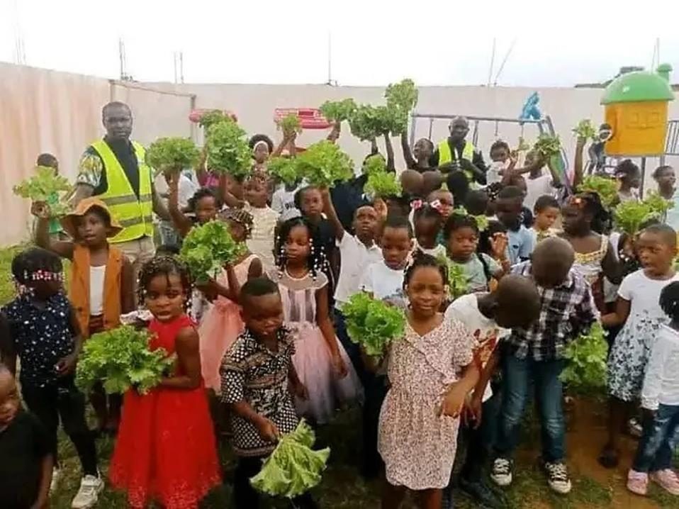 Les enfants brandissant la récolte du jardin scolaire — opération SODAGRI, juin 2026